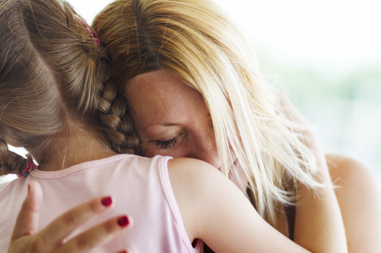 Emotional hugging between mother and daughter. Rear view, genuine family.