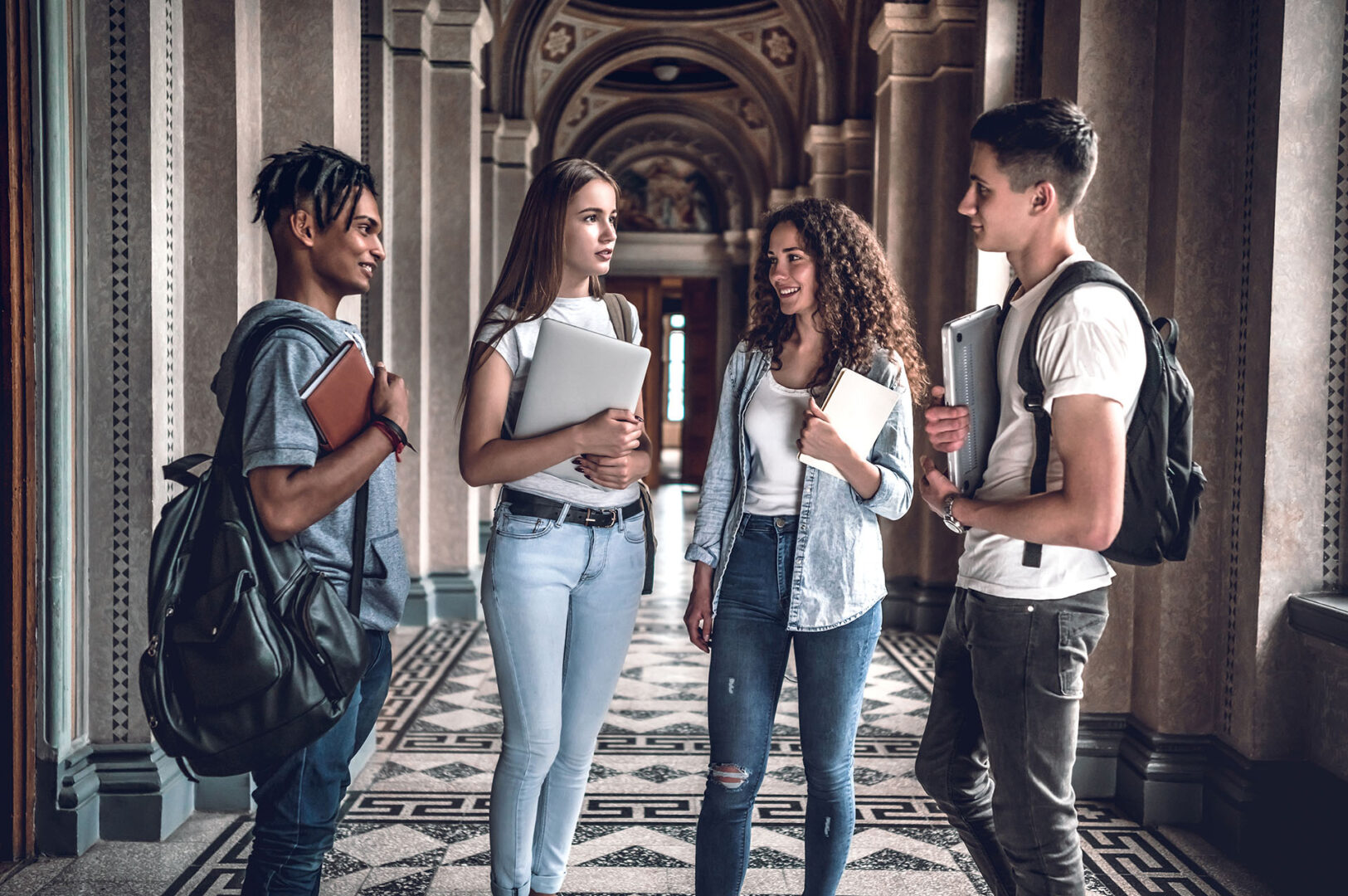 Students life. Four beautiful students chatting each other in the university.