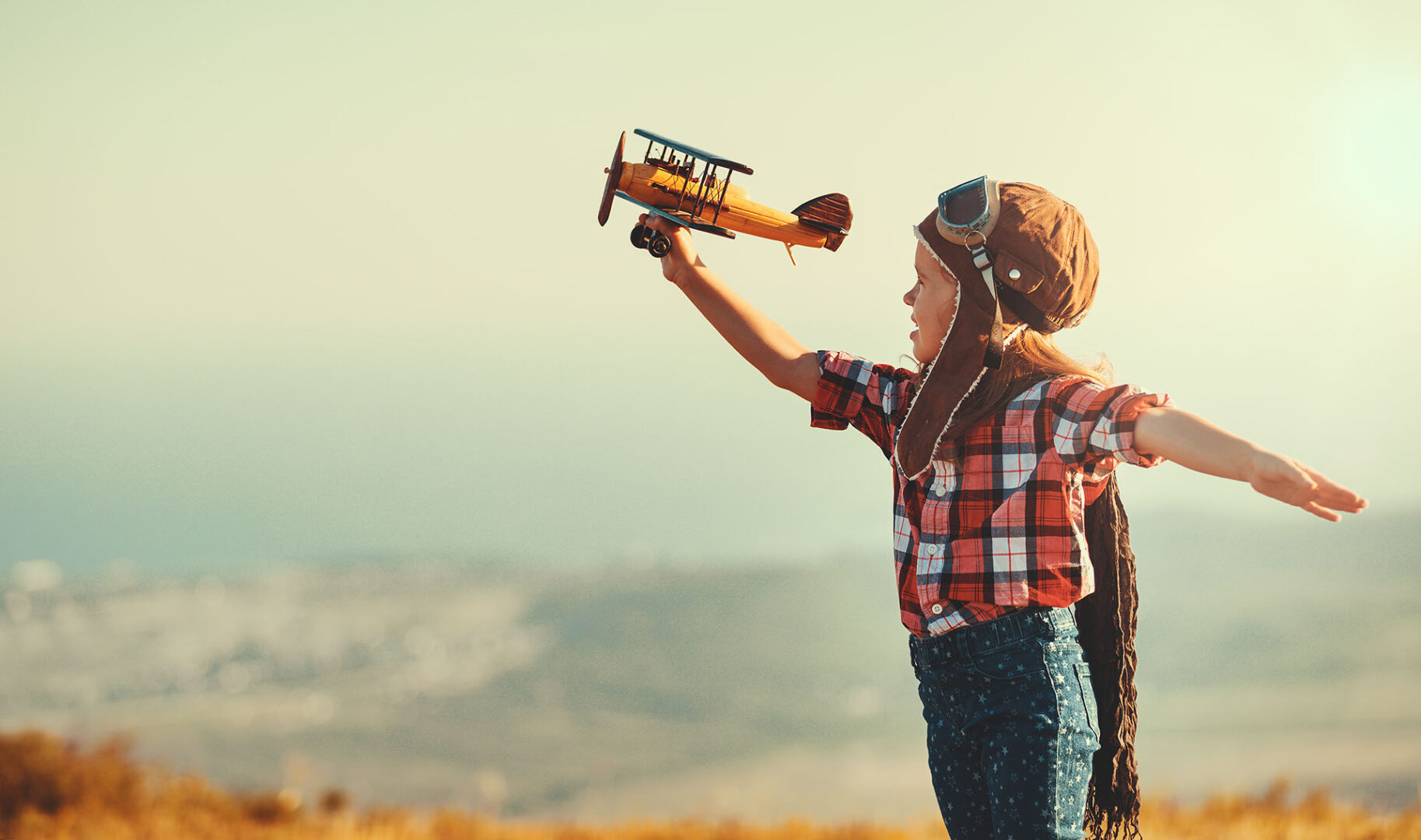 Child pilot aviator with airplane dreams of traveling in summer in nature at sunset