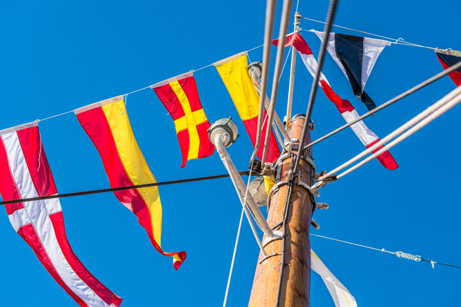 Signal flags hanging off the mast on a wooden boat.