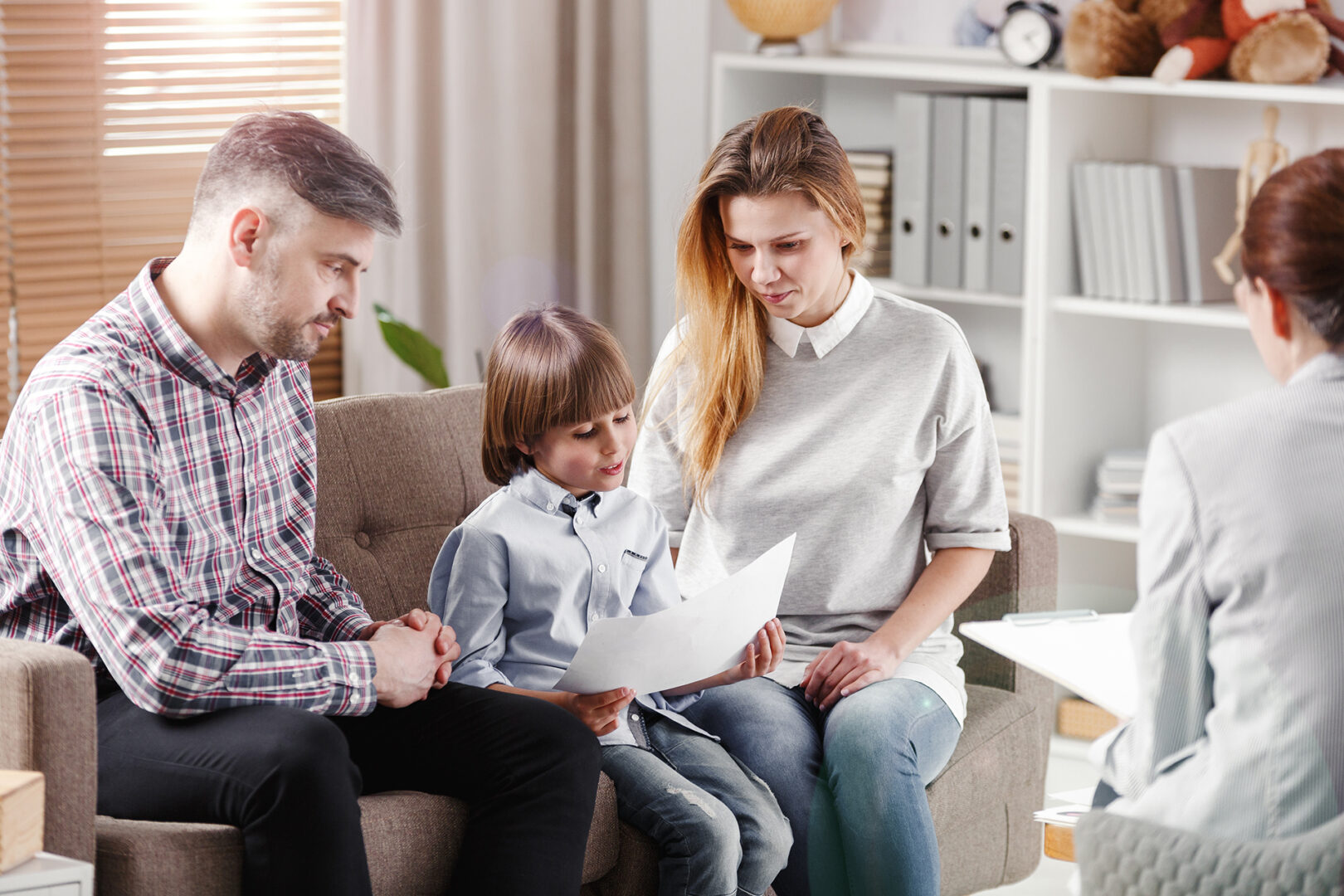 Autistic boy describing picture while sitting with parents during consultation with therapist